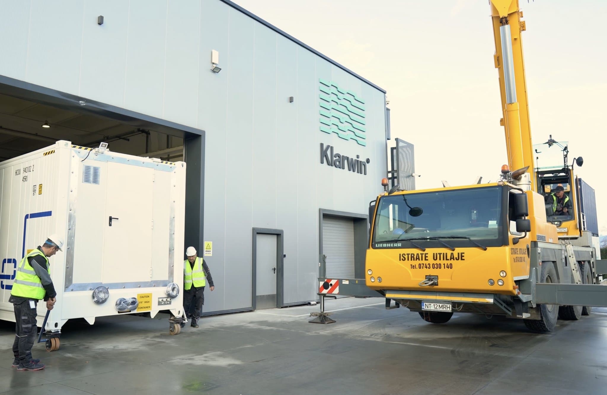 Container Klar100 încărcat cu o macara Liebherr în fața clădirii Klarwin PRO din Iernut