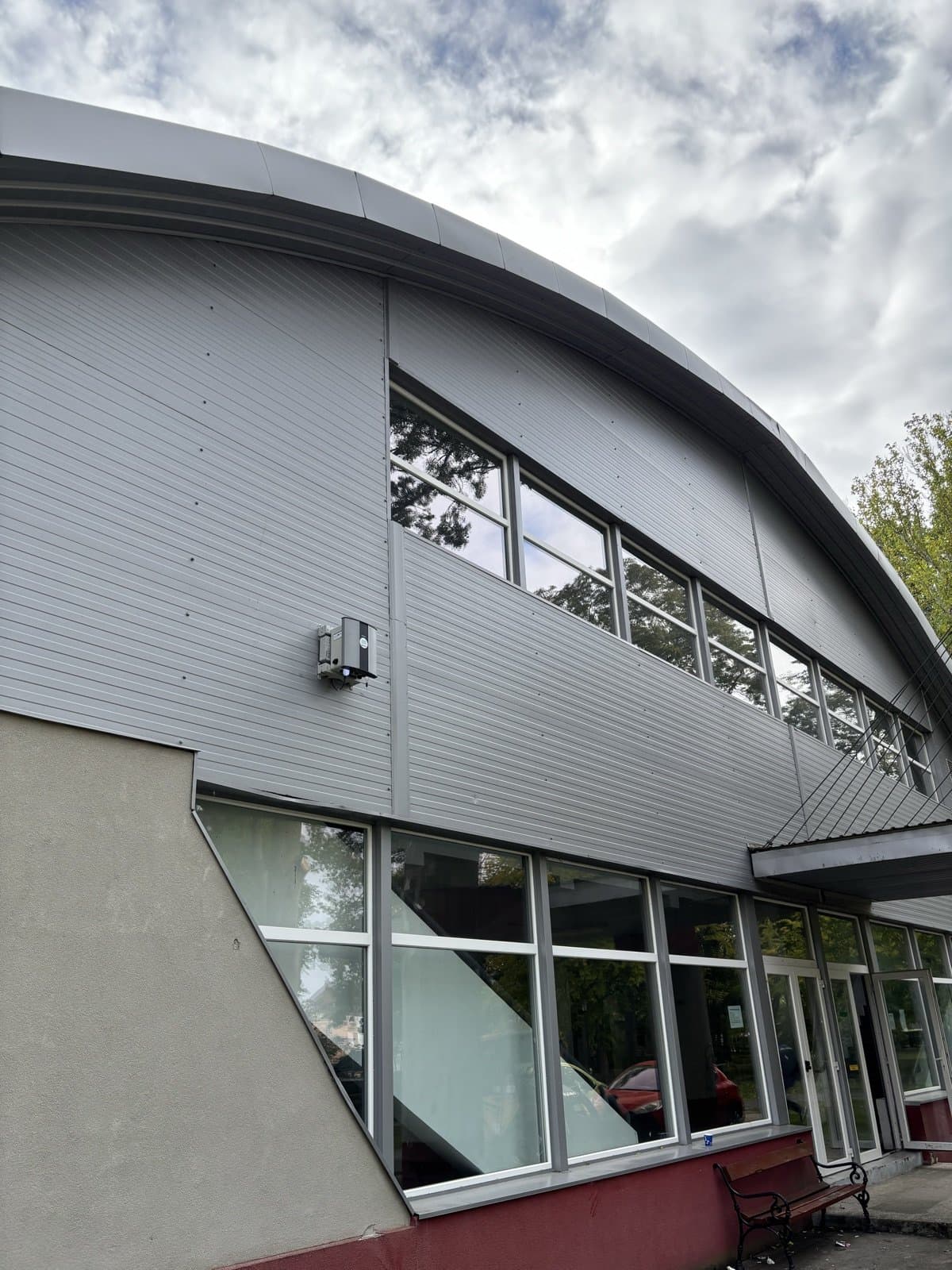 Oizom Polludrone air quality station mounted on a modern curved-roof public building